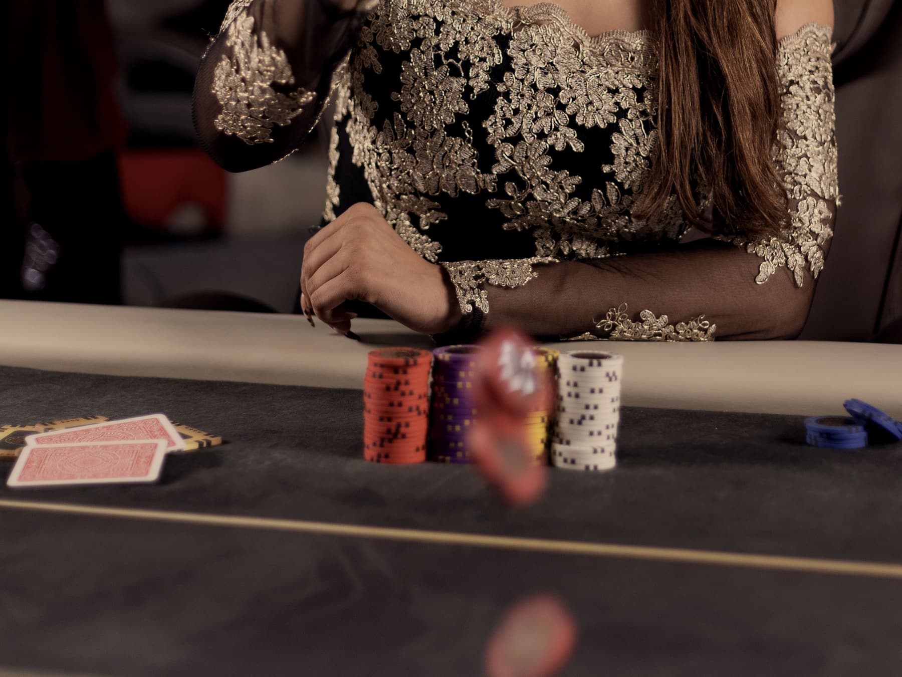A chip caught in the air above the felt, cards face down beneath it.