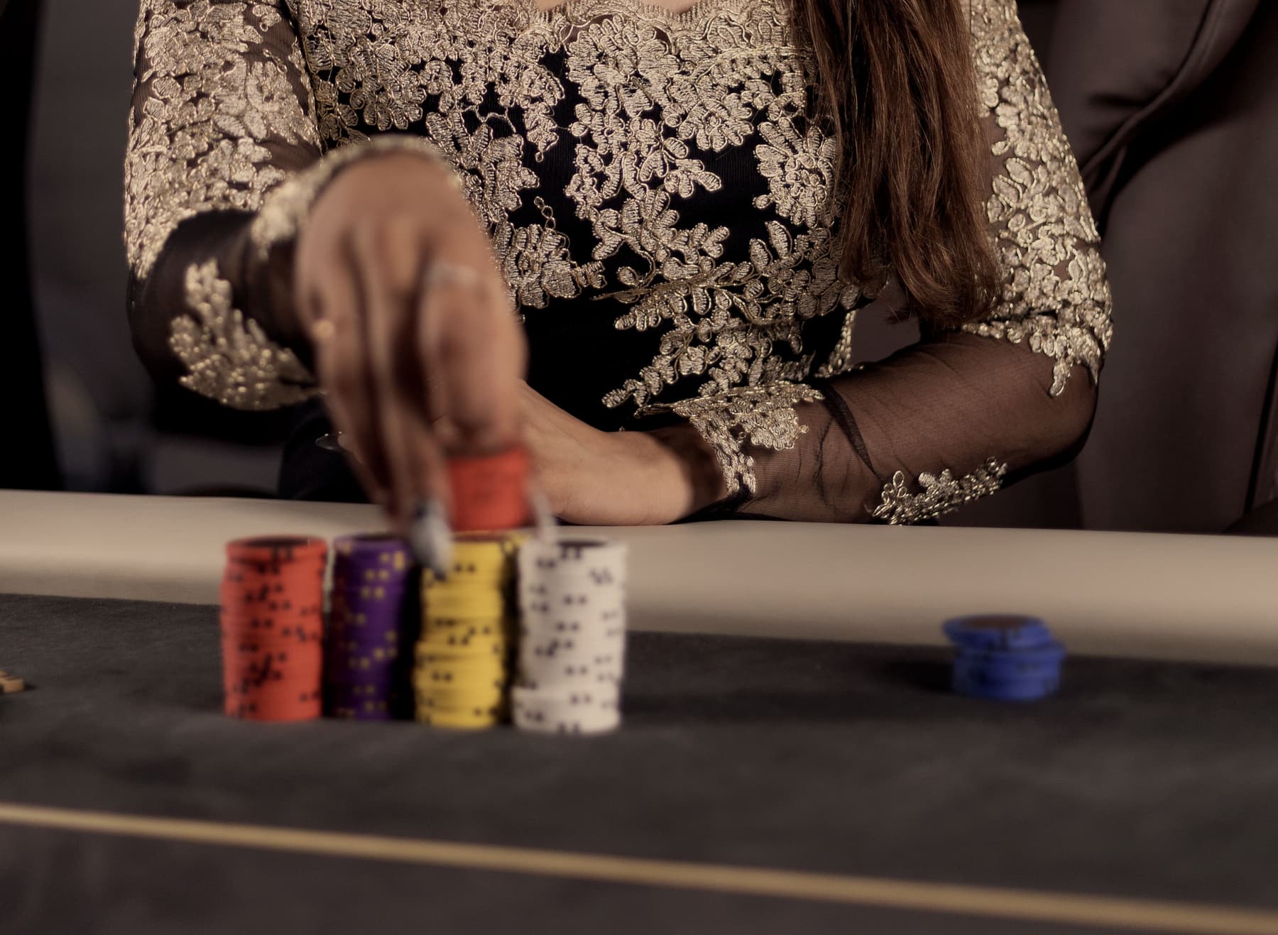 A hand reaching across the felt to place a short stack of chips.