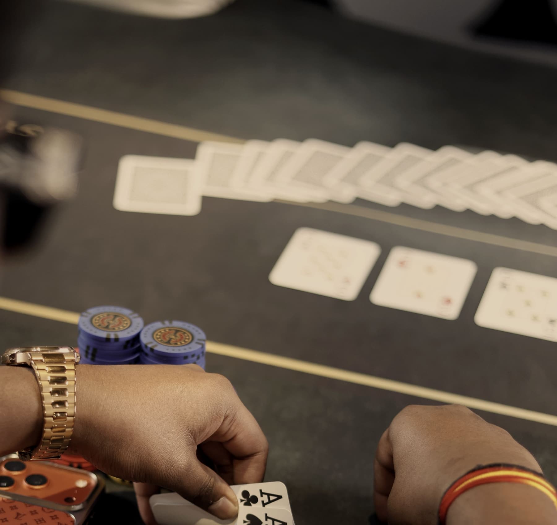 Pocket aces held over the felt beside a short stack of chips.