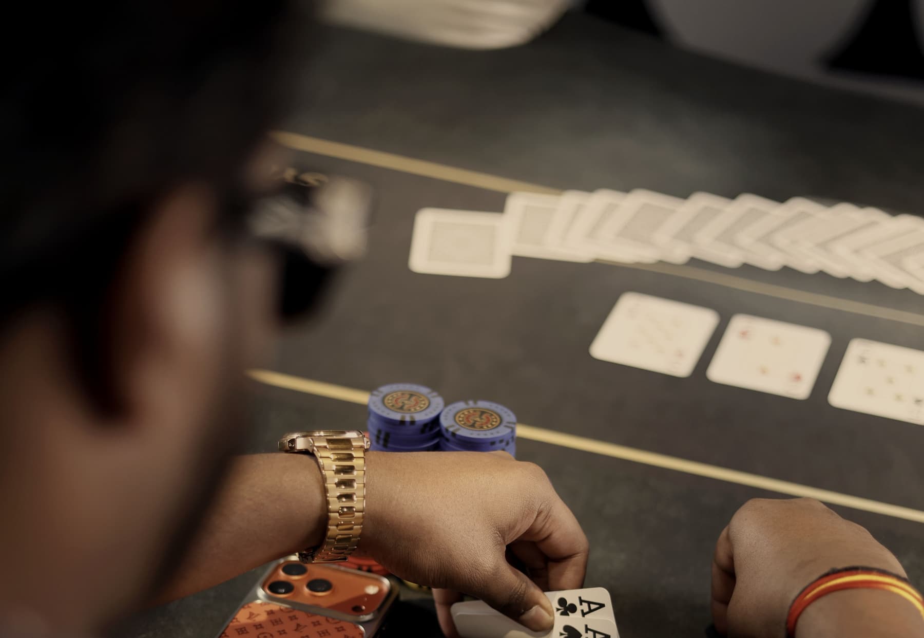 Pocket aces held low over dark felt beside a stack of chips, the board runout laid out beyond.