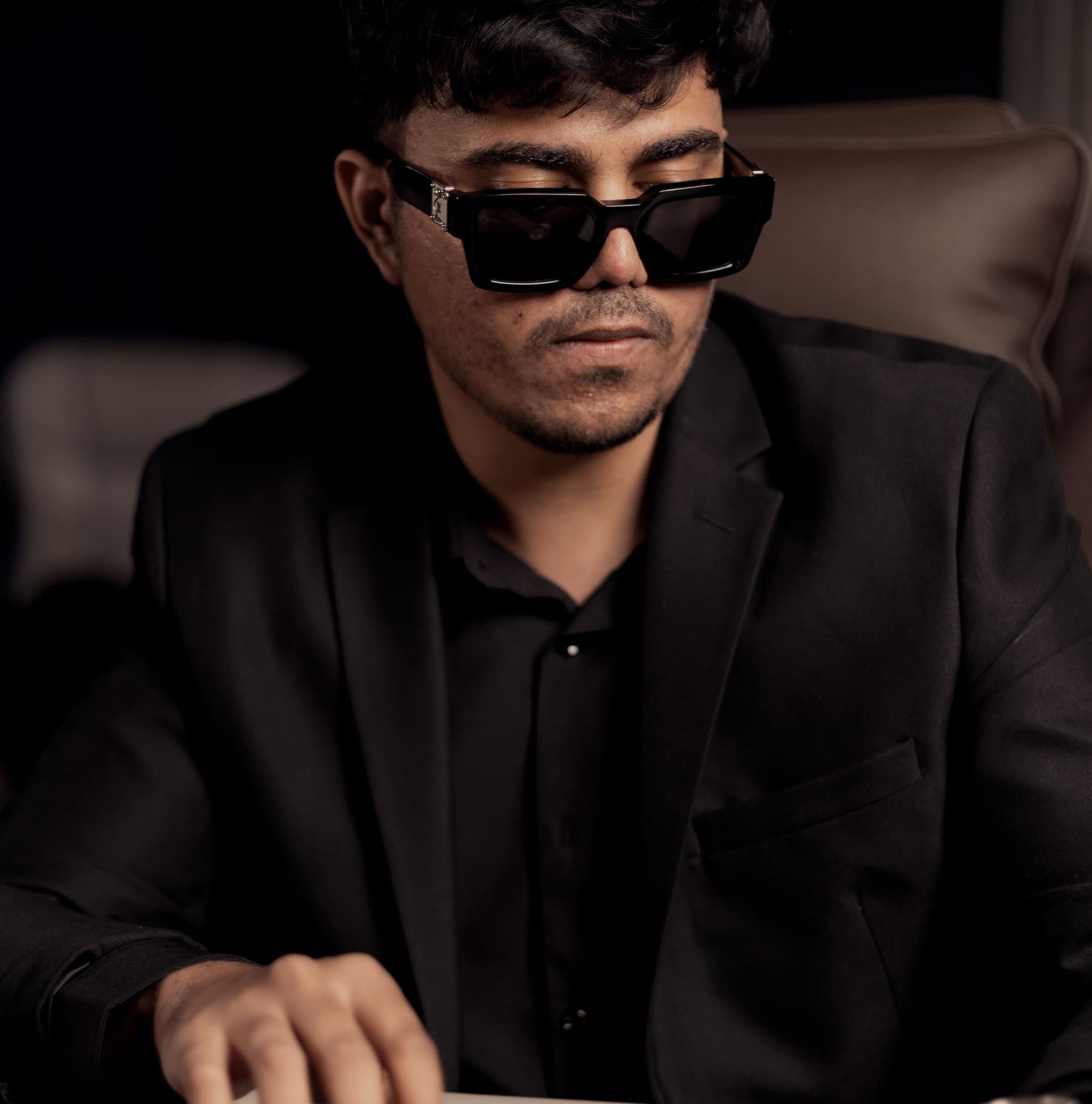 A player sitting back in low light, one hand resting over their cards.