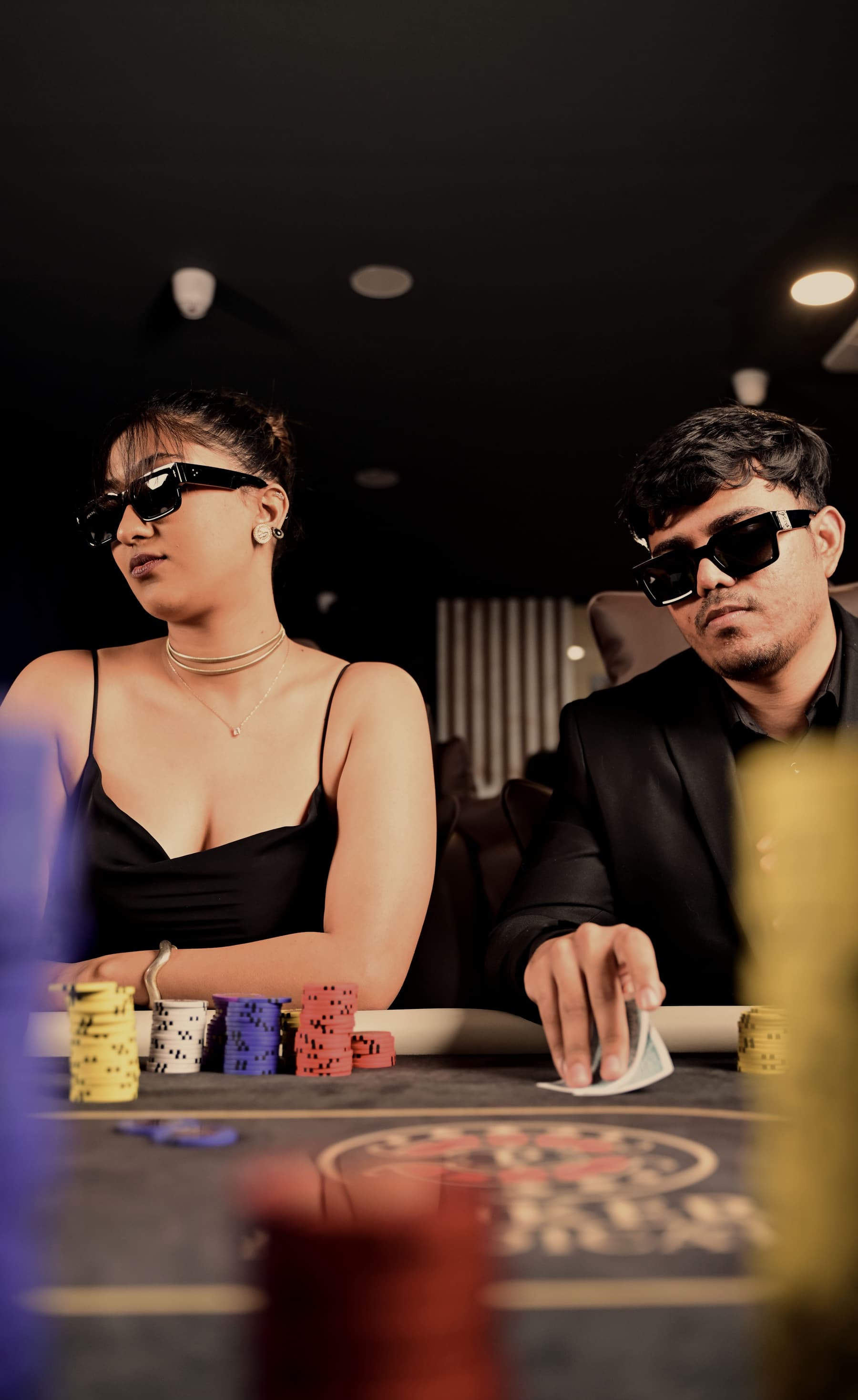 Two players side by side at the table mid-conversation, chips stacked in front of them.