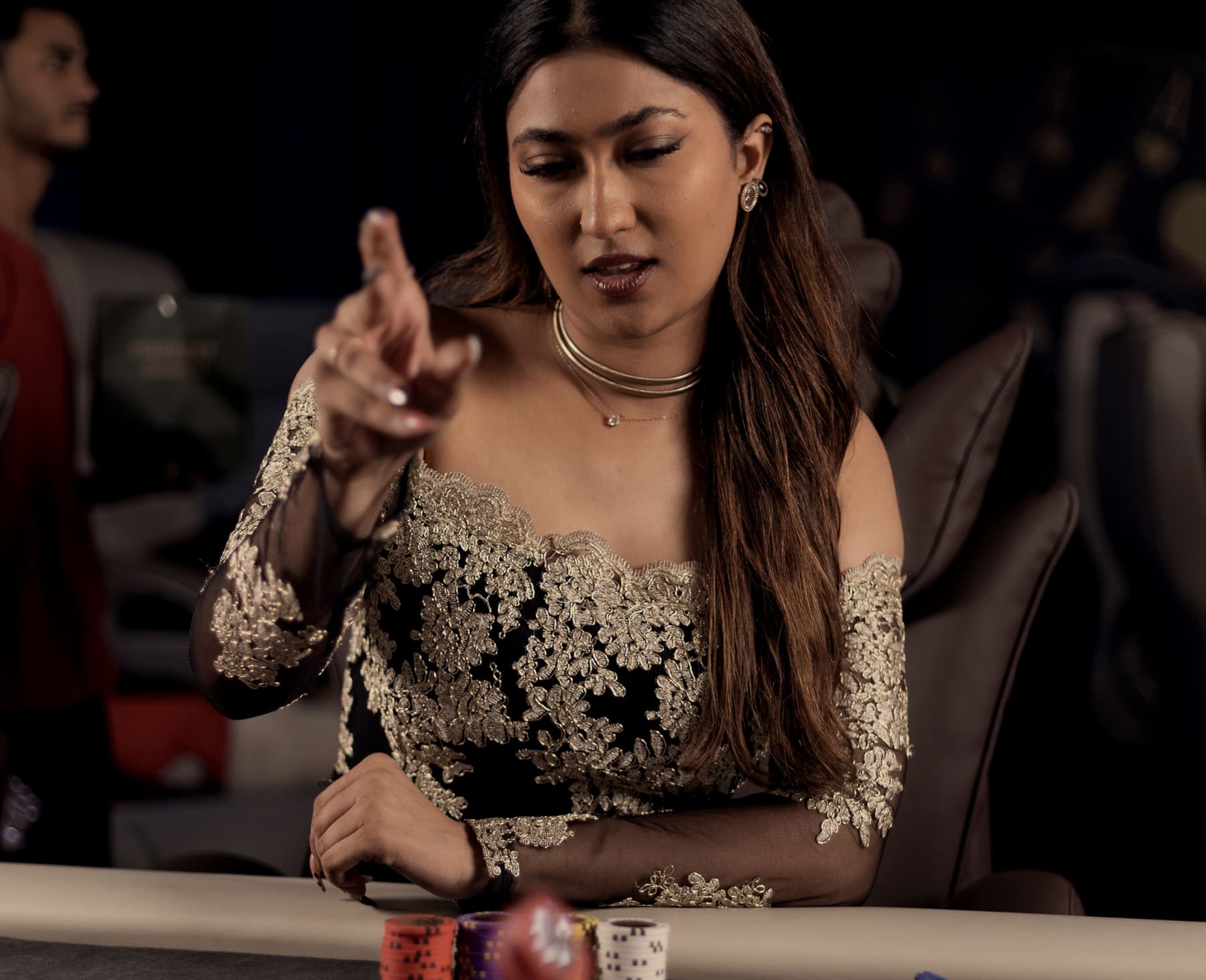 A player at the rail gesturing to the dealer, cards face down on the felt.