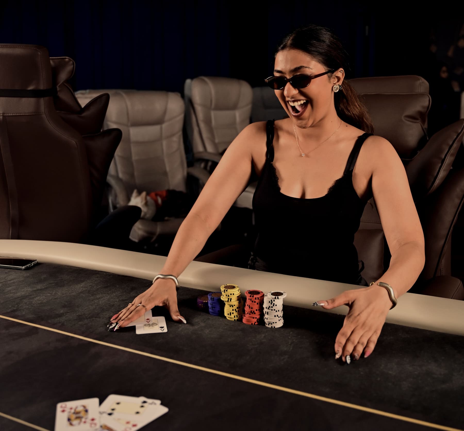 A wide view of the room: a felt table with gold trim, leather recliners, a player reaching for chips.